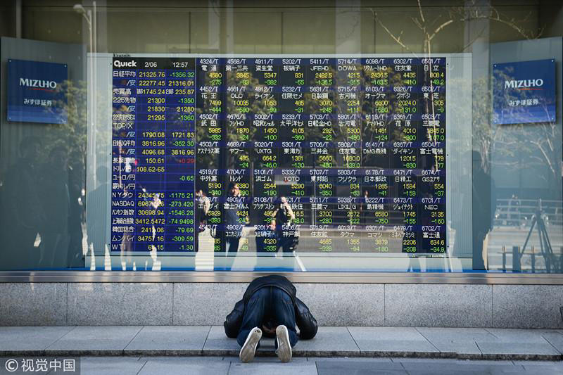 日本东京,一位市民在显示股市下跌信息的告示牌跪拜(来源:视觉中国)