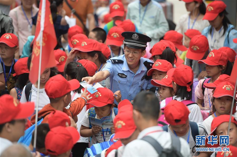 7月3日，在永济北站，一名民警向候车的留守儿童发放安全乘车手册。当日，在山西运城永济市举办的“爱在路上”亲情护送活动中，260余名留守儿童在志愿者的护送下从火车永济北站出发，前往北京与父母团聚。