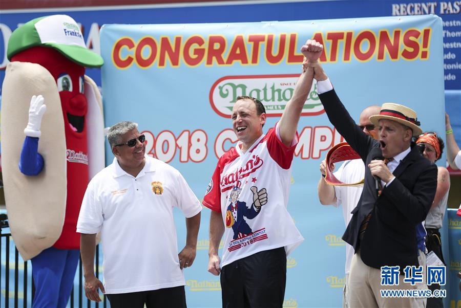 7月4日，在美国纽约康尼岛，选手乔伊·切斯特纳特（中）庆祝吃热狗大赛夺冠。