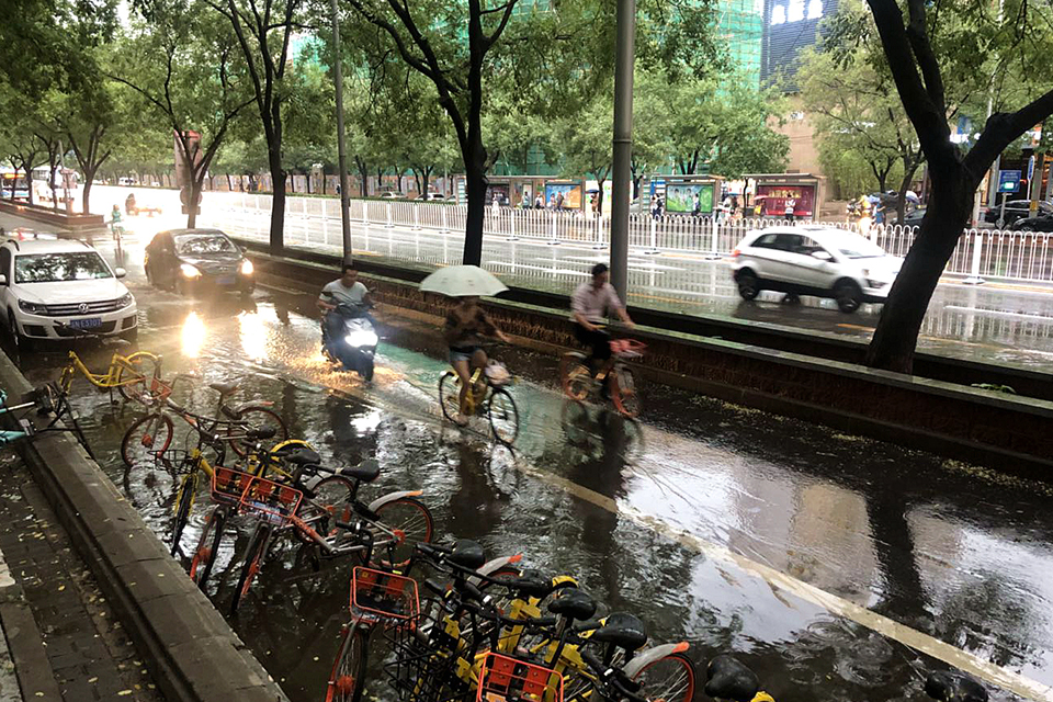 大雨天，有骑行者在前，机动车并没有催促。