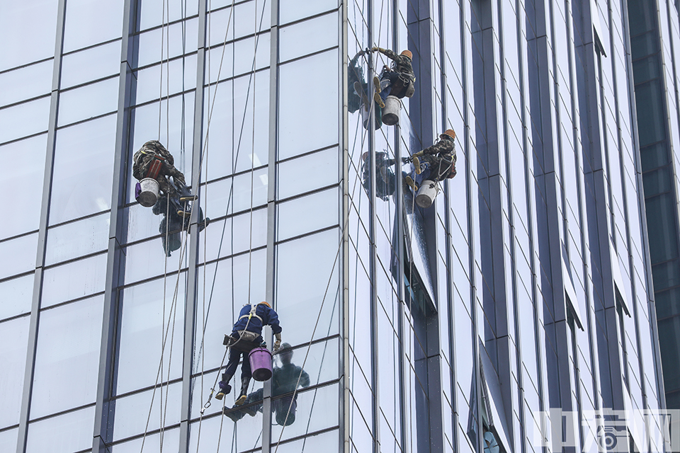 9月12日，在北京西站附近的一处写字楼，数名“蜘蛛人”系着保险绳，悬吊在距地面数十米的高空处，对写字楼玻璃外墙进行清洁。 中宏网记者 富宇 摄