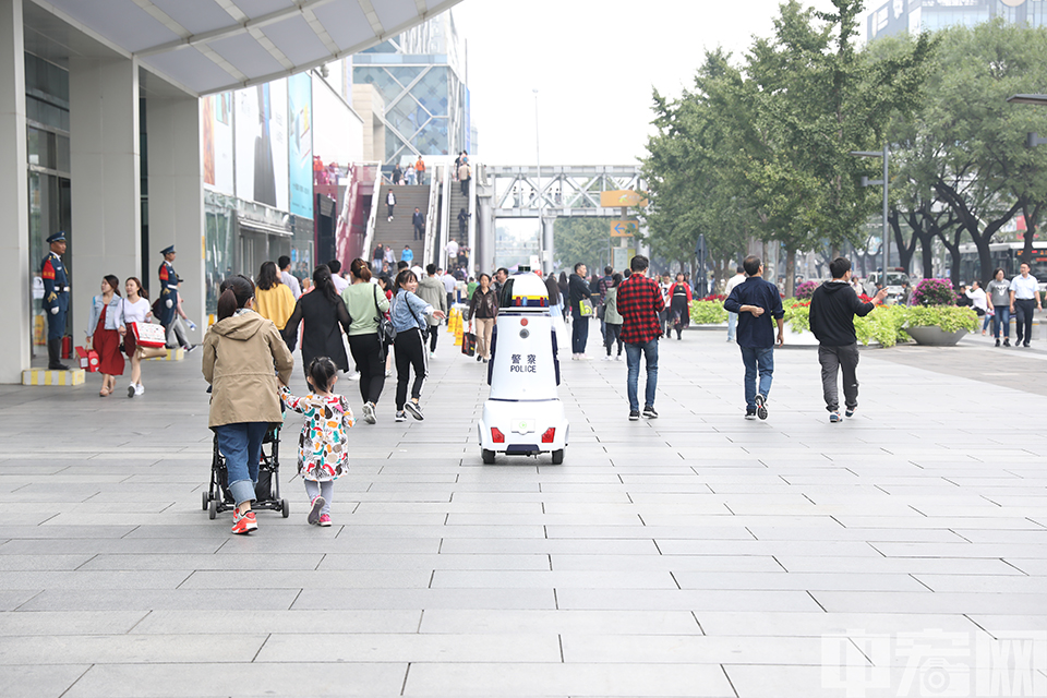 9月27日，在北京西单商业区，一台机器人“警察”出现在来往的人群中“上岗执勤”，吸引了众多市民驻足。记者在现场看到，这台机器人上装有摄像头，扬声器，照明灯，报警灯和轮子等，显得科幻风十足。据了解，这款警用机器人是由公安部第一研究所研制。 中宏网记者 富宇 摄