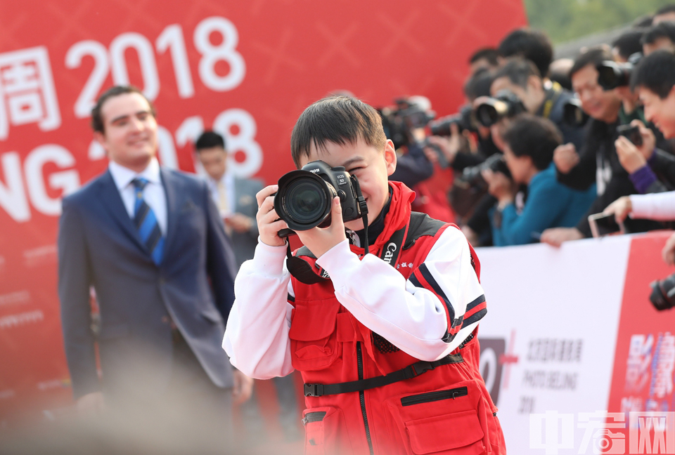10月20日，北京国际摄影周2018在中华世纪坛开幕，国际摄影艺术联合会，国内外知名摄影周节创办人、重要摄影艺术机构负责人、知名摄影师及本次摄影周策展人等100余位嘉宾依次走上开幕红毯，成为开幕式上的最大亮点。图为红毯上的小摄影师。 中宏网记者 康书源 摄