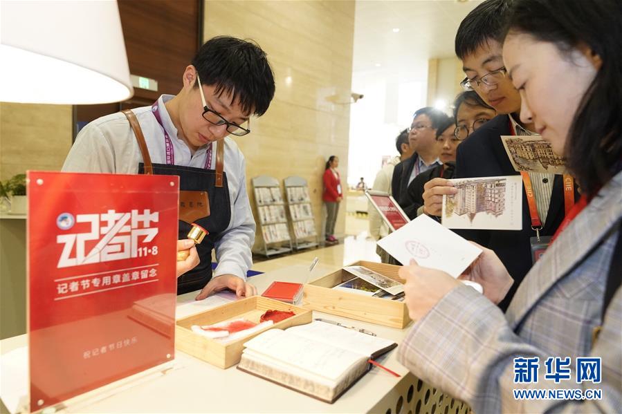 11月8日，工作人员在进博会新闻中心为记者们在明信片上盖章留念。  新华社记者 沈伯韩 摄