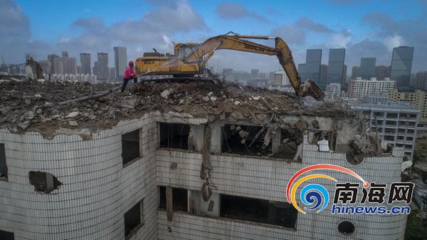 12月6日，挖掘机在海口市红城湖片区棚改建筑物22层66米高的八达大厦上进行拆除。 图片来源：南海网