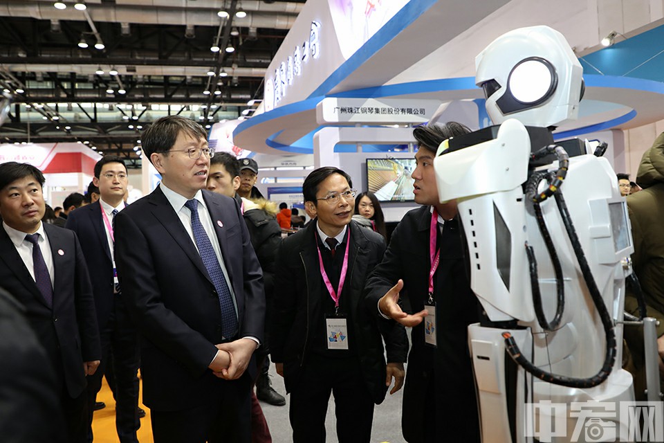 12月14日，北京国家会议中心，参展商向中华全国总工会书记处书记曲昭伟介绍机器人产品。