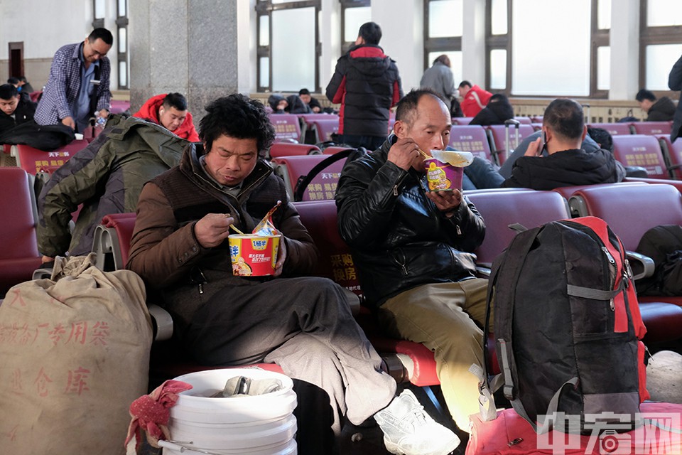 1月21日，北京火车站候车室，两名正在等待列车的旅客吃起泡面。