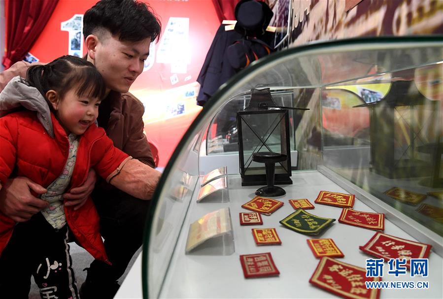 1月21日，一名体验者在郑州火车站带孩子观看展出的不同时期不同岗位的铁路工作人员臂章。新华社记者李安摄
