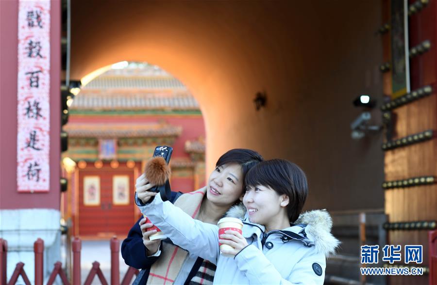 1月21日，游客在贴有春联的故宫神武门前自拍。新华社记者金良快摄