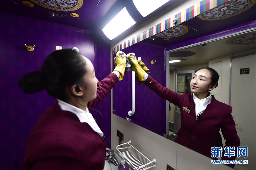 1月21日，旦增央金在擦拭旅客车厢洗漱台镜子。 在青藏铁路“唐竺古道号”Z6811次列车的乘务团队中，有一对藏族姐妹。姐姐贡久曲珍2007年参加工作，现在是该次列车的列车长；妹妹旦增央金2017年开始在列车上担任乘务员。从青海西宁到西藏日喀则的春运旅途上，姐妹俩用真诚的服务温暖着旅客的回家路。 新华社发（张龙摄）
