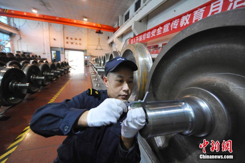 质检员汪召坤对火车车轮进行检修。 彭琦 摄 图片来源：中新网