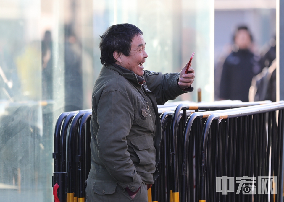 一位旅客对着手机，露出爽朗的笑容。 中宏网记者 富宇 摄