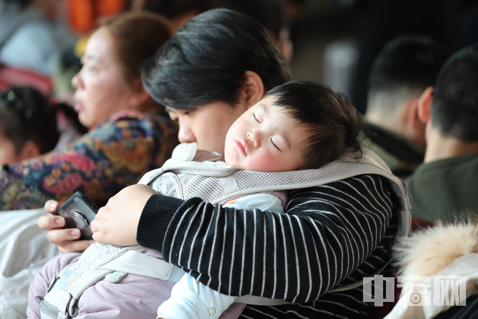 这位家长抱娃玩手机两不耽误，怀里的孩子还睡得很香。 中宏网记者 富宇 摄