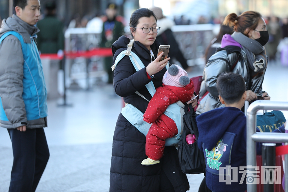 【带娃神器：婴儿背带】孩子靠在母亲怀里，母亲还能腾出手来看看微信。 中宏网记者 富宇 康书源 摄