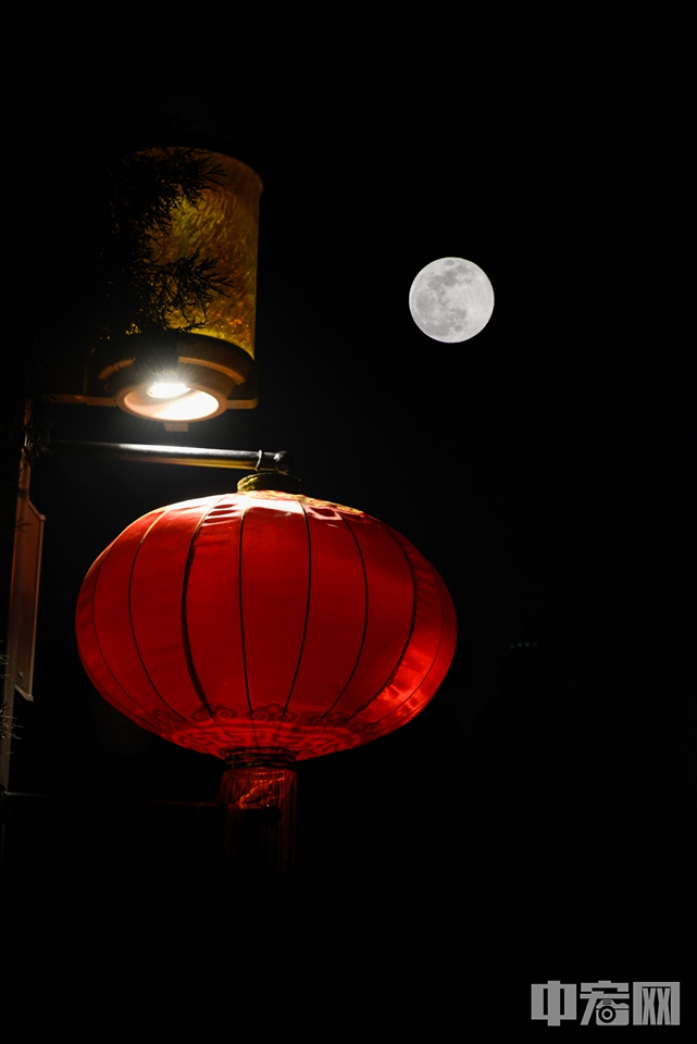“超级月亮”与红灯笼相映成趣。（多重曝光） 中宏网记者 富宇 摄