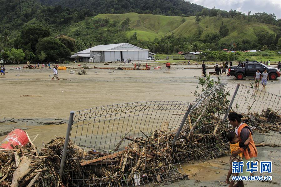 3月17日，在印度尼西亚巴布亚省森塔尼，一名妇女抱着孩子站在被洪水冲垮的围栏旁。<br/>

　　印度尼西亚抗灾署17日说，印尼东部巴布亚省16日晚发生的洪涝灾害已导致42人死亡、21人受伤。<br/>

　　新华社发
