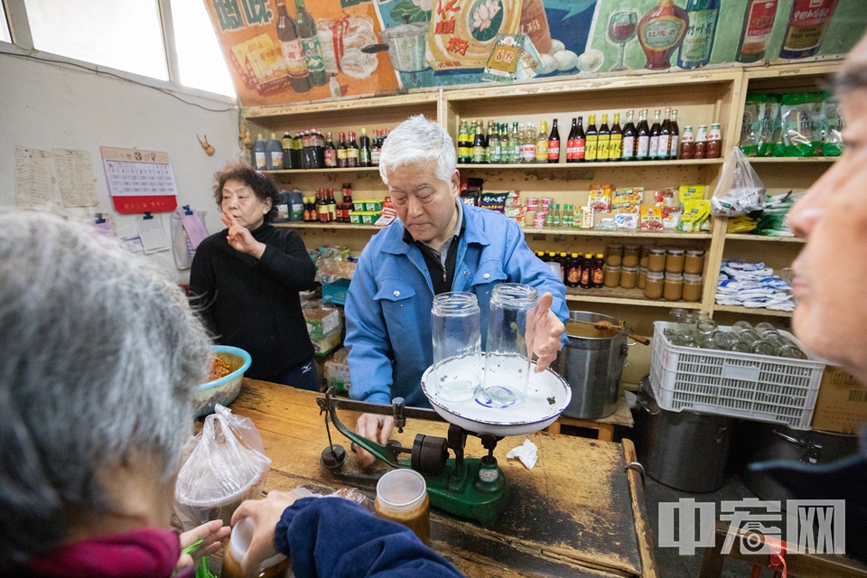 有些老顾客会自带瓶子罐子买麻酱，李师傅就会用老式秤先称好重量，再去打麻酱。 中宏网记者 富宇 摄