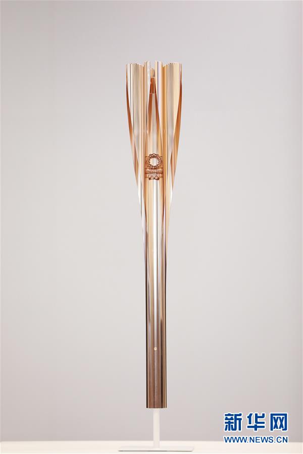 3月20日，东京奥组委在日本东京揭晓了2020年东京奥运会火炬样式。东京奥运火炬造型的灵感源自樱花，颜色为“樱花金”，火炬顶部设计成花瓣状，奥运火种将从五个“花瓣”及中央“花蕊”部分点燃。火炬整体长度为71厘米，总重量约1.2公斤。火炬主要材质为铝材，采用了使用在新干线制造中的铝挤压工艺。 这是3月20日在发布会上拍摄的东京奥运会火炬。 新华社记者杜潇逸摄