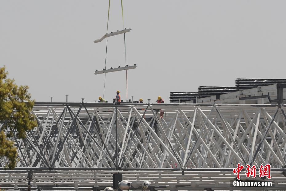 图为建设者在吊装钢结构屋顶。张亨伟 摄 图片来源：中新网