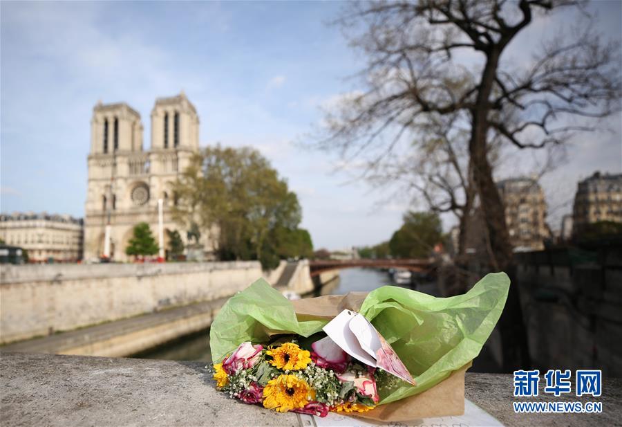 4月18日，在法国巴黎，人们为巴黎圣母院献上鲜花。法国总统马克龙16日晚发表简短电视讲话时表示，希望在5年内重建巴黎圣母院。“法国人民是建造者，将重建更加瑰丽的巴黎圣母院。”截至17日中午，法国各界为重建和修复巴黎圣母院承诺的捐献金额已超过8.25亿欧元。 新华社记者 高静 摄