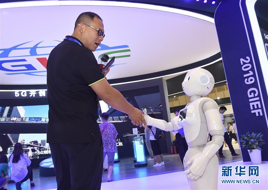 6月11日，一名参观者在与机器人握手。 6月10日至12日，2019成都全球创新创业交易会在成都举行，一系列科技产品亮相此次交易会，吸引众多观众前来参观体验。 新华社记者 刘坤 摄