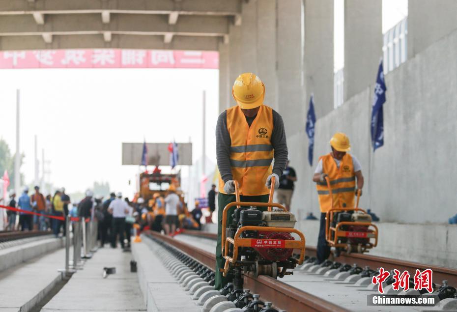 工人使用螺丝机紧固钢轨。 中新社记者 贾天勇 摄