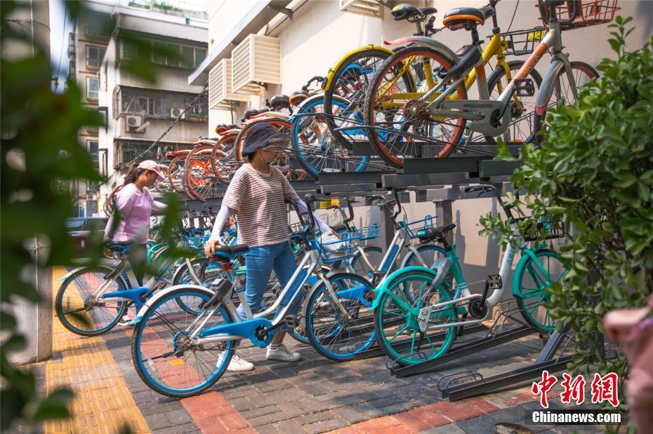 近日,一座双层共享单车立体停车器亮相郑州市中原区计划路街头,停车器上整齐摆放着各个品牌的共享单车,整齐划一。图为市民使用完共享单车后将其停放在立体停车器上。张为涛 摄