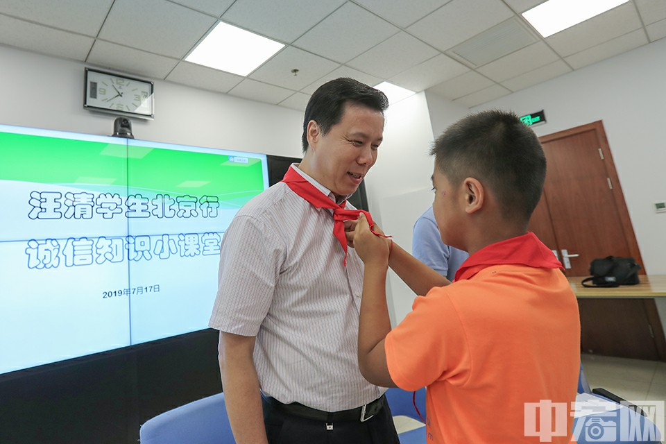 通过此次诚信知识小课堂，汪清县的小学生们从听、感受、说等多角度更深层次地感受到诚信的力量。今天在心中埋下一颗诚信的种子，明天将在成长的路上生根发芽。图为孙文轩小朋友给陈洪宛司长系上红领巾。中宏网记者 康书源 摄