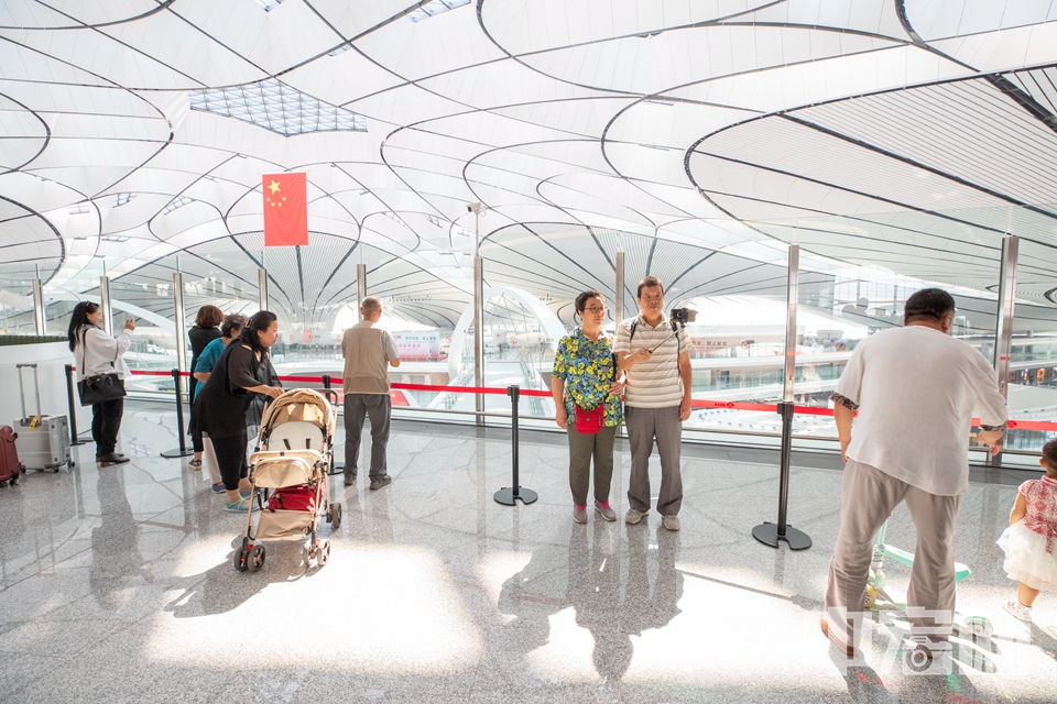 近日，新开放的大兴国际机场成为了不少民众的游览景点。据统计，“高颜值”的大兴国际机场国庆期间共迎来51.84万人次的“打卡游客”。仅10月3日当天，游客数量就达到10.7万人次，是出行旅客的23倍。为服务好参观游客，大兴机场在公共区新开多家餐厅，提供与市区“同质同价”的服务。图为在大兴机场游览拍照的市民。（资料图） 中宏网记者 富宇 摄
