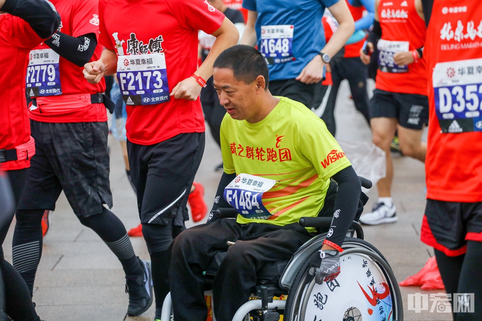 一名残疾人士滑动着轮椅参加北京马拉松。