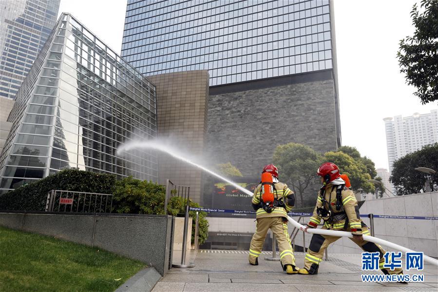 11月13日，消防员在演练中对位于裙楼的“着火点”喷水。新华社记者 刘颖 摄