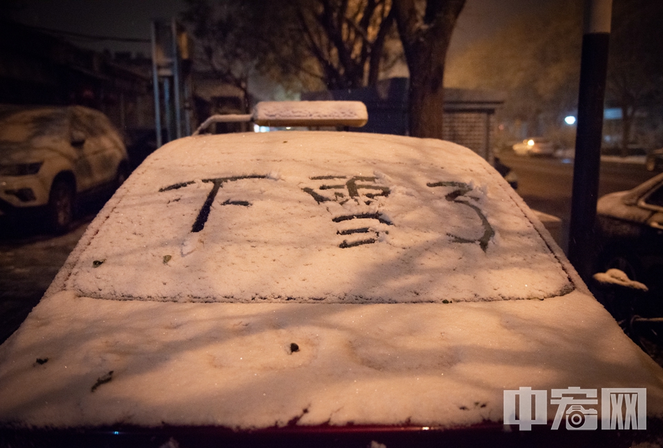 激动的市民在汽车玻璃上写下“下雪了”三个字。 中宏网记者 富宇 摄