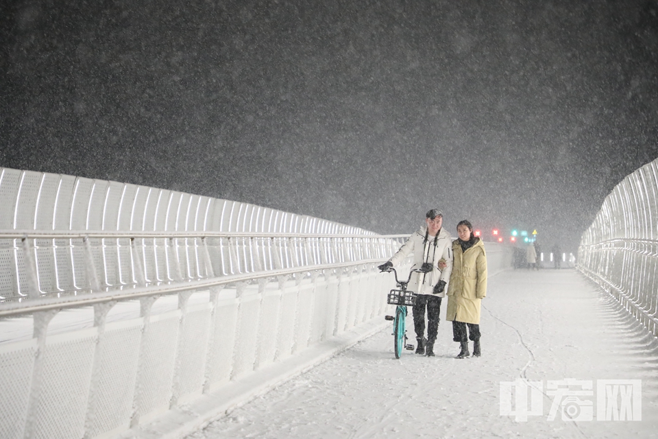 在北京回龙观地区，一对年轻人在积雪满满的天桥上拍照。 中宏网记者 康书源 摄