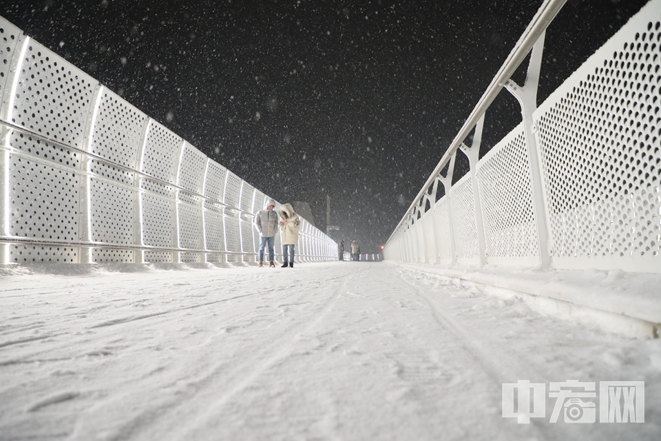 在北京回龙观地区，一对年轻人在积雪满满的天桥上拍照。 中宏网记者 康书源 摄