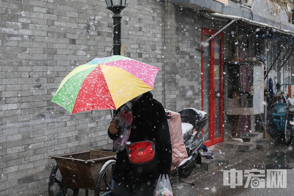 12月15日傍晚开始，北京迎来第二场降雪。16日，漫步在老胡同中，雪中的京味儿格外浓。图为民众在雪中出行。 中宏网记者 富宇 摄