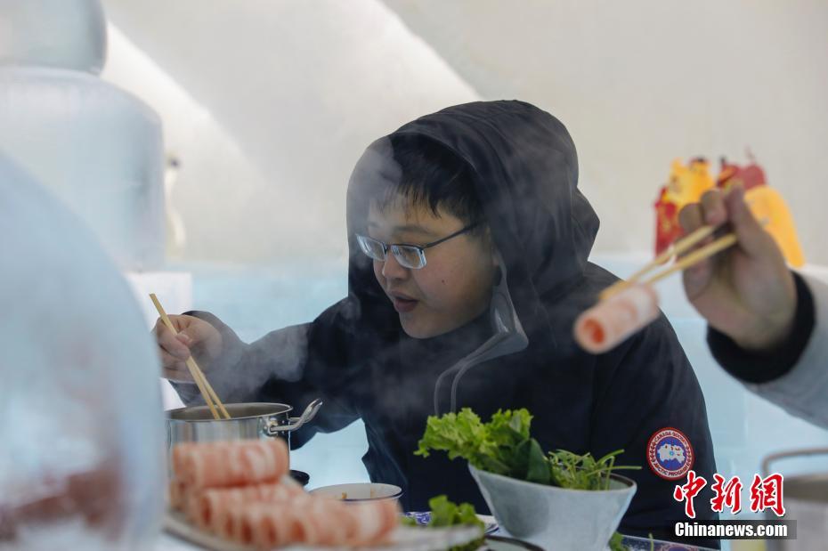 1月11日，游客在哈尔滨冰雪大世界室园区内的冰屋涮火锅、喝啤酒，用冰塑造的房屋、桌椅、吧台、酒杯等物品显得晶莹别致。