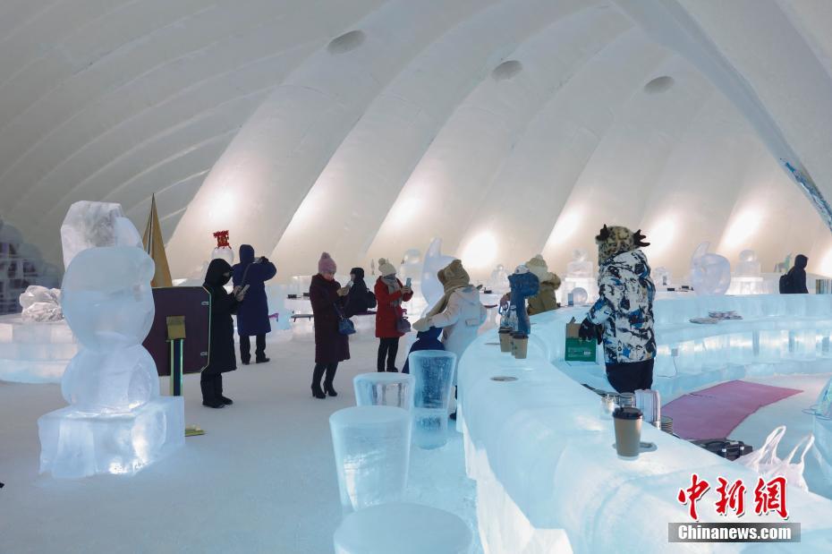 1月11日，游客在哈尔滨冰雪大世界室园区内的冰屋涮火锅、喝啤酒，用冰塑造的房屋、桌椅、吧台、酒杯等物品显得晶莹别致。图为游客参观冰屋火锅。