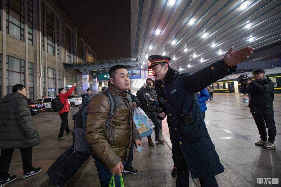 1月10日0点，北京站工作人员为检票后的旅客引导车厢方向。
