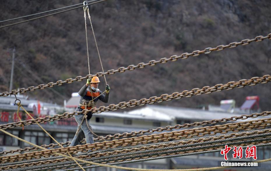 铁索桥维修老工人王齐学正在检查铁索桥桥板安装情况。 刘忠俊 摄