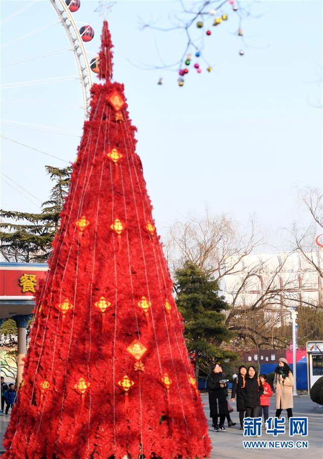 1月19日，游客经过北京石景山游乐园的“福”字装饰树。 春节将至，北京石景山游乐园张灯结彩，装饰一新，并筹备多项主题游园活动喜迎佳节。 新华社记者 李俊东 摄