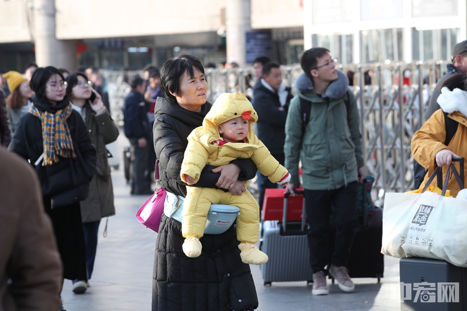 小宝宝在家人的怀抱里走向了火车站。中宏网记者 富宇 摄