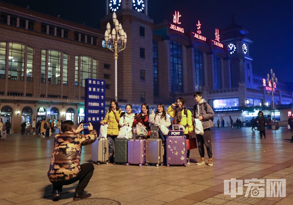 根据铁路部门的预测，从今日起到春节假期前一天(1月23日)，北京各大火车站将迎来节前春运的最高峰。在春运路上，许多旅客纷纷拿起手机拍下春运瞬间。图为春运首日，旅客在北京站广场上拍合影。 中宏网记者 康书源 摄
