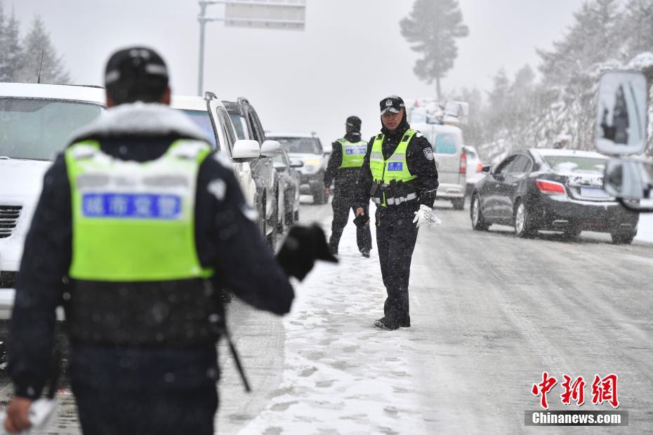 1月20日，云南迪庆藏族自治州香格里拉市突降大雪，交警坚守在214国道重点路段指挥疏导交通，保障春运路上过往车辆安全行驶。中新社记者 刘冉阳 摄