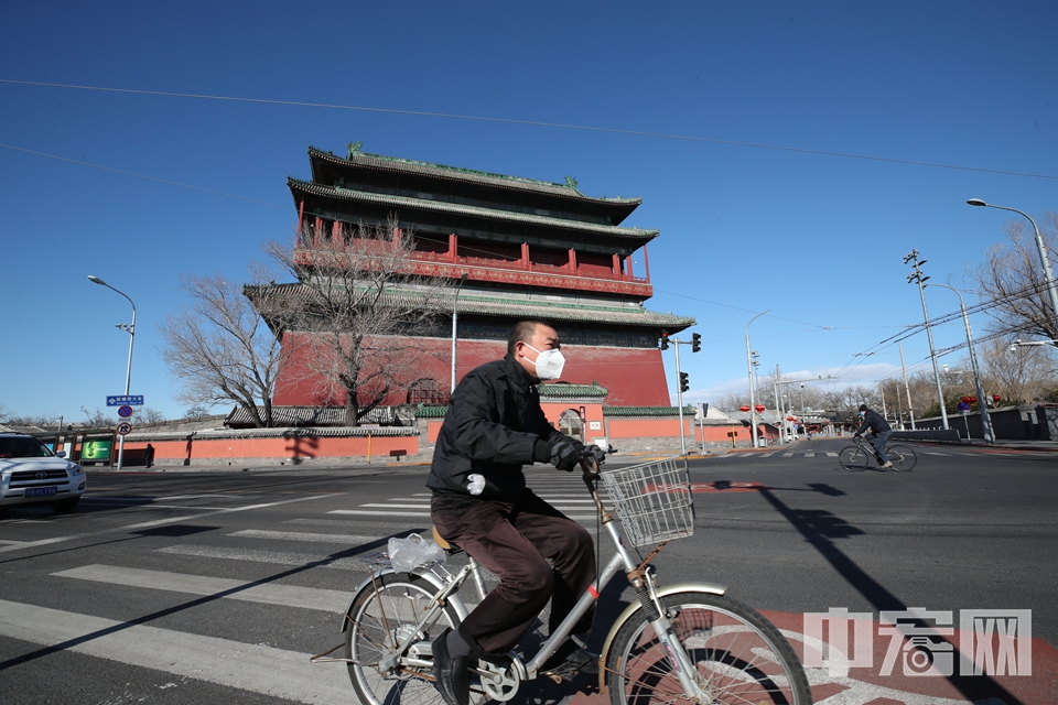 2月16日，行走在北京街头，行人稀少。图为一位戴口罩的市民从鼓楼前骑车经过。 中宏网记者 富宇 摄