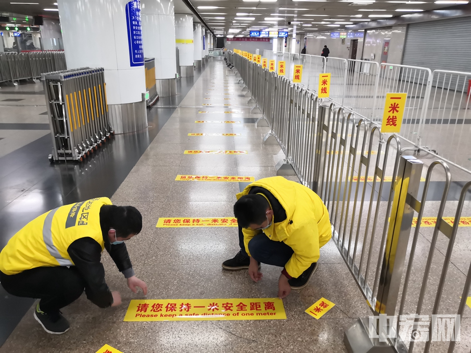 近日，为了防控疫情，减少人员聚集，北京西站，北京站，北京南站和北京北站等各大火车站均在候车区等地面区域设置了一米线，以便让旅客之间保持安全距离。图为工作人员正在北京西站地下地铁进站区域粘贴一米线指示标。