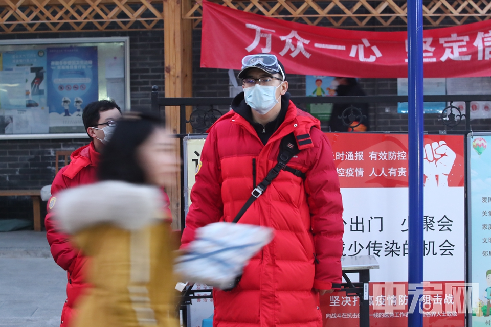 晚上6点，天色已黑。陈硕与居委会主任仍然值守在小区入口，并对一位未戴口罩的居民进行劝返。 中宏网记者 富宇 摄