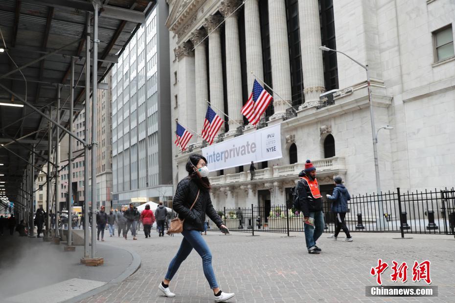 当地时间3月12日，一位戴口罩的民众走过纽约证券交易所。当日，纽约股市三大股指开盘出现暴跌，跌幅超过7%。暴跌行情导致美股再次触发熔断机制，暂停交易15分钟。中新社记者 廖攀 摄