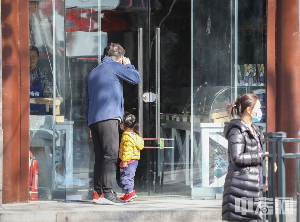 一对父女在关门的店铺外张望。 中宏网记者 富宇 摄