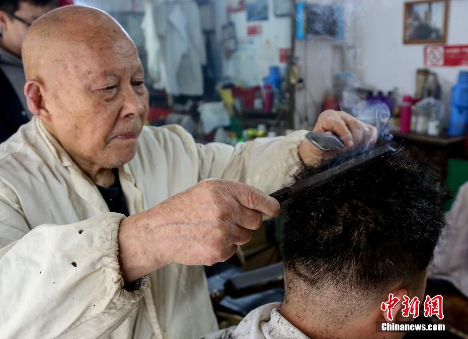 3月6日,理发师黄文祥老人一手拿着火钳,一手拿着梳子,熟练地在客人