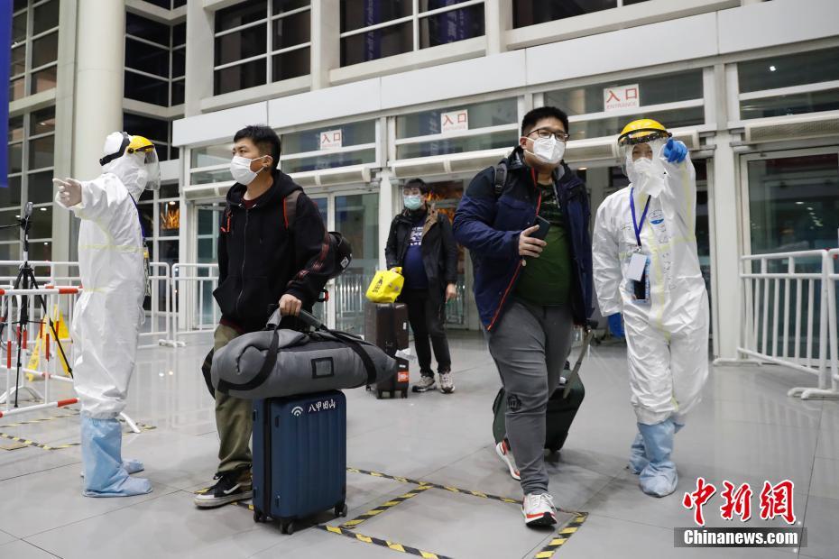 3月23日，位于北京中国国际展览中心新馆的检查入境人员集散点内，旅客拖着行李走进集散点，工作人员上前进行指引。中新社记者 韩海丹 摄